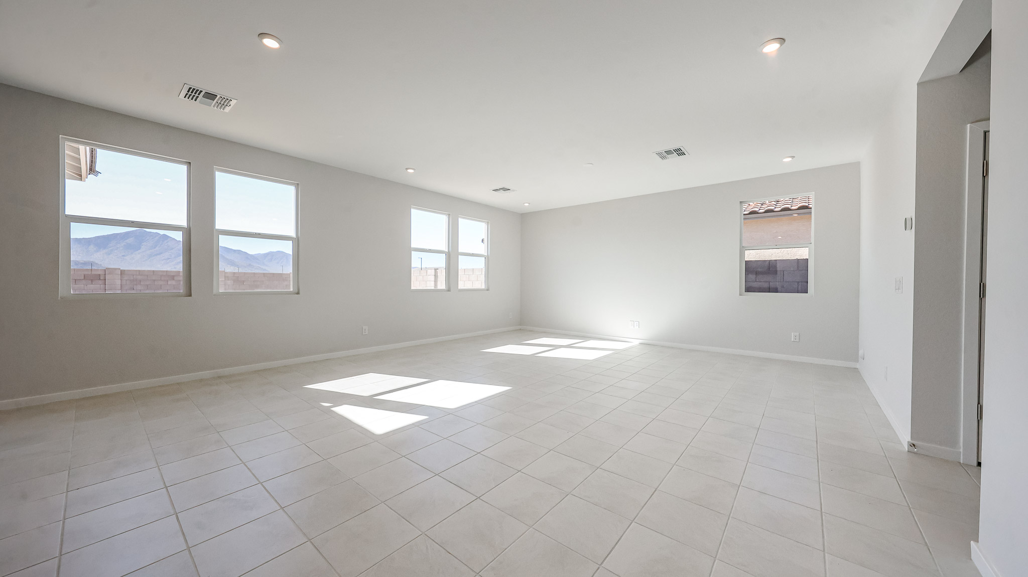 A large empty room with a tile floor and large windows.