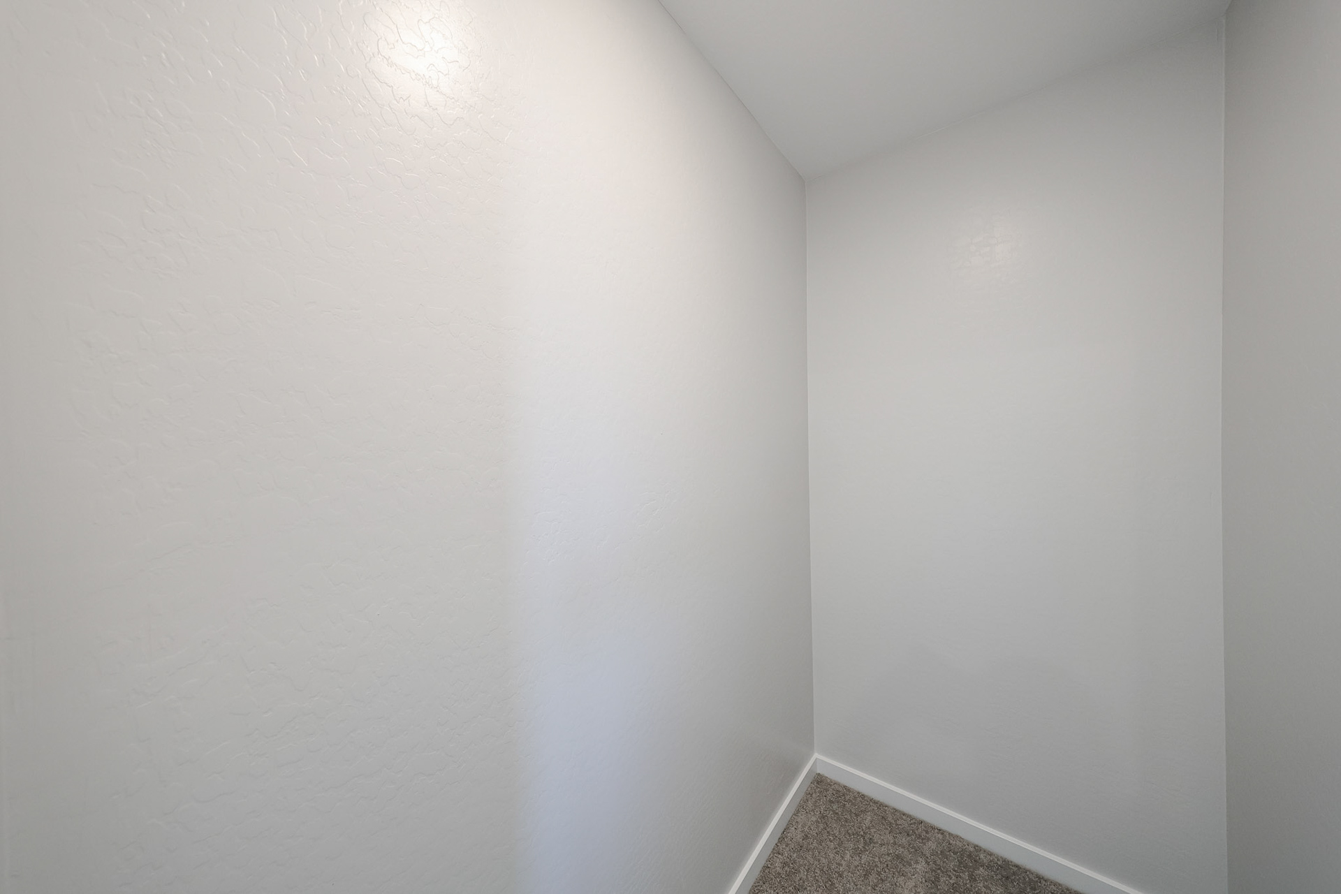 A white wall with a brown carpet.