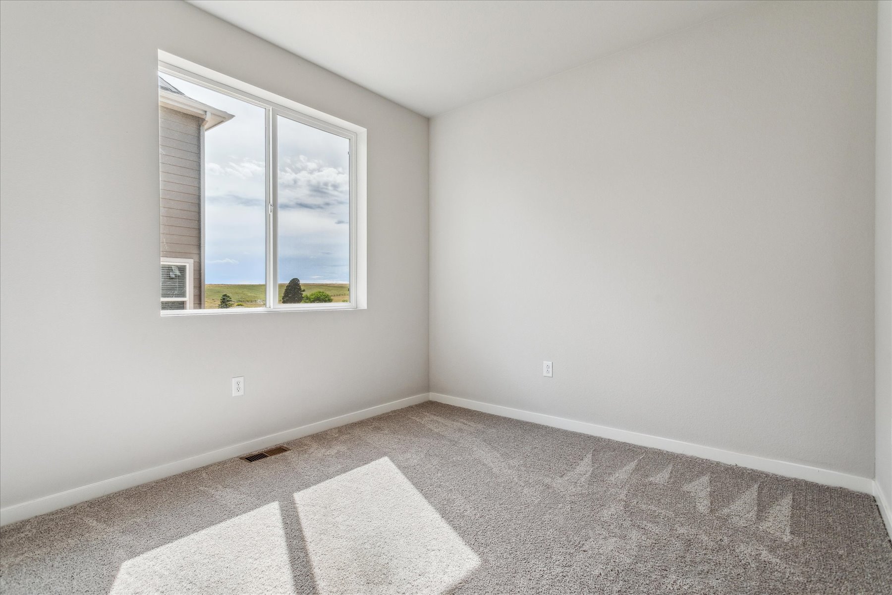 A room with a window and a rug.
