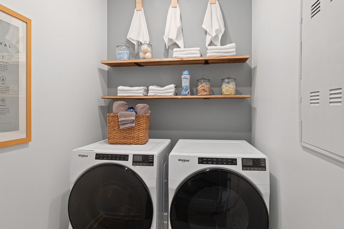 A white laundry room with a shelf and a white laundry basket.