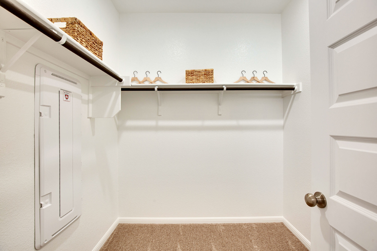 A white room with a shelf and a basket on the wall.