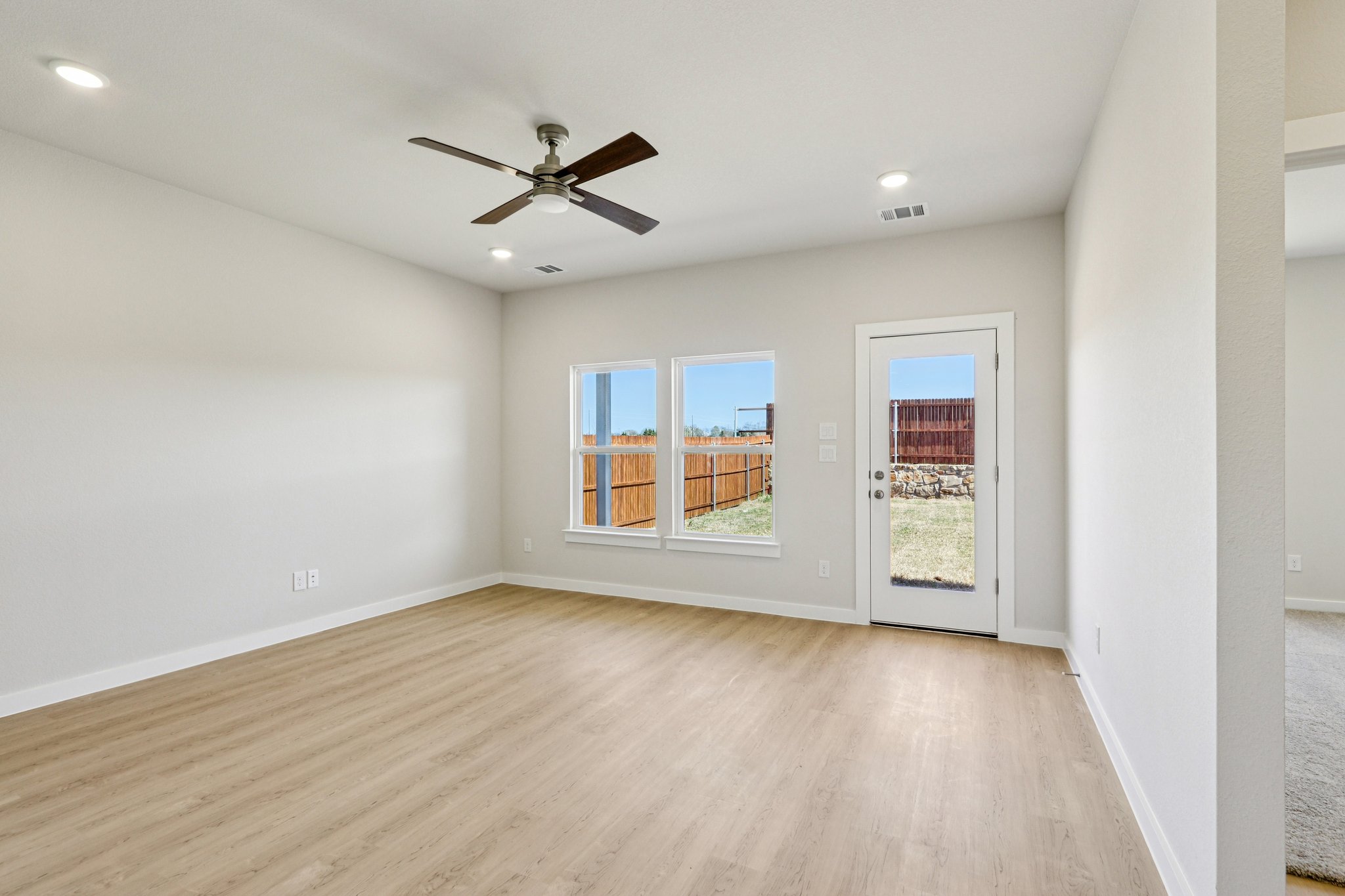 A room with a wood floor and a ceiling fan and a wood floor.