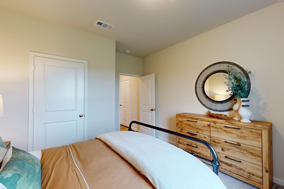 A bedroom with a mirror and a bed.