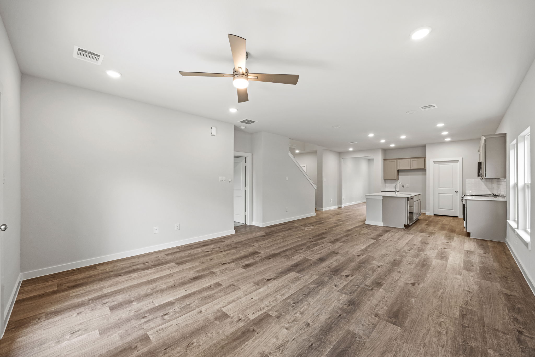 A large empty room with a wood floor and a ceiling fan.