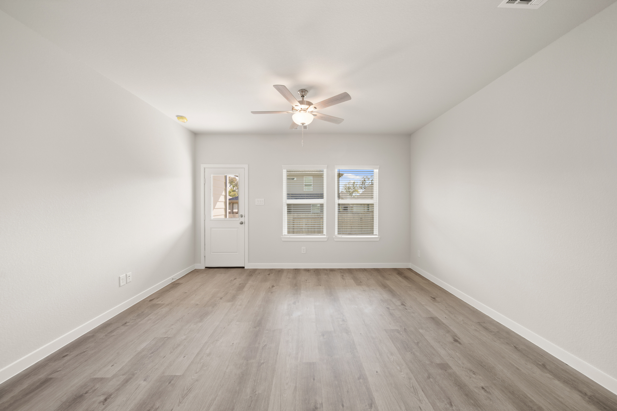 A room with a ceiling fan and a wood floor.