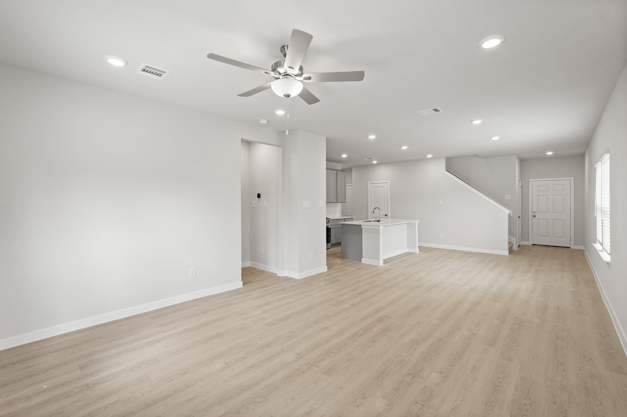 A large empty room with a ceiling fan and a wood floor.