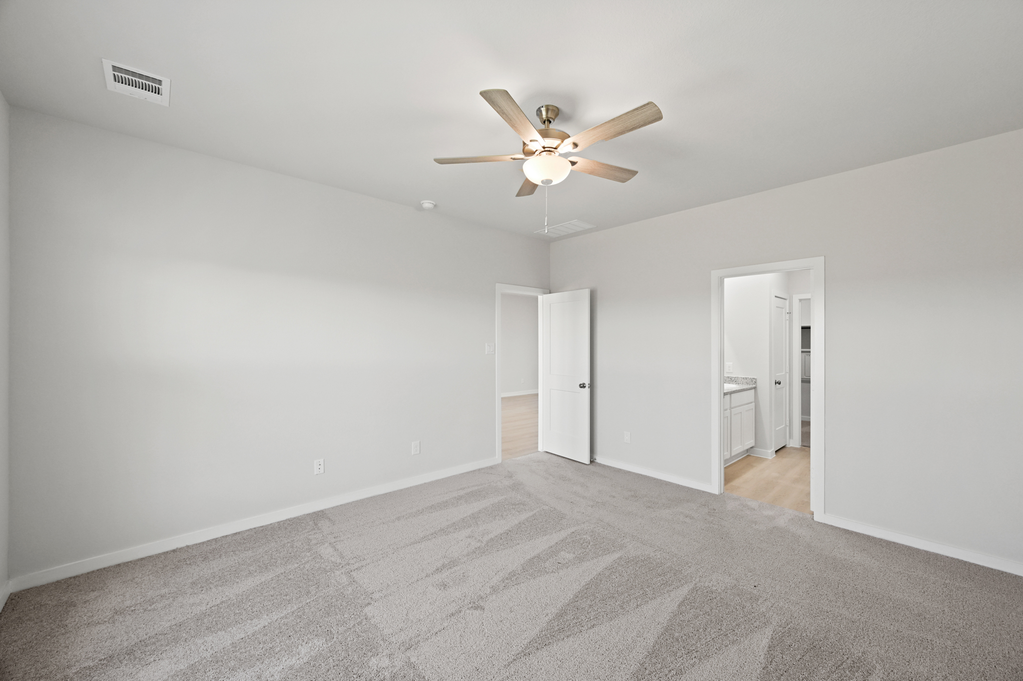 A room with a ceiling fan and a carpet.