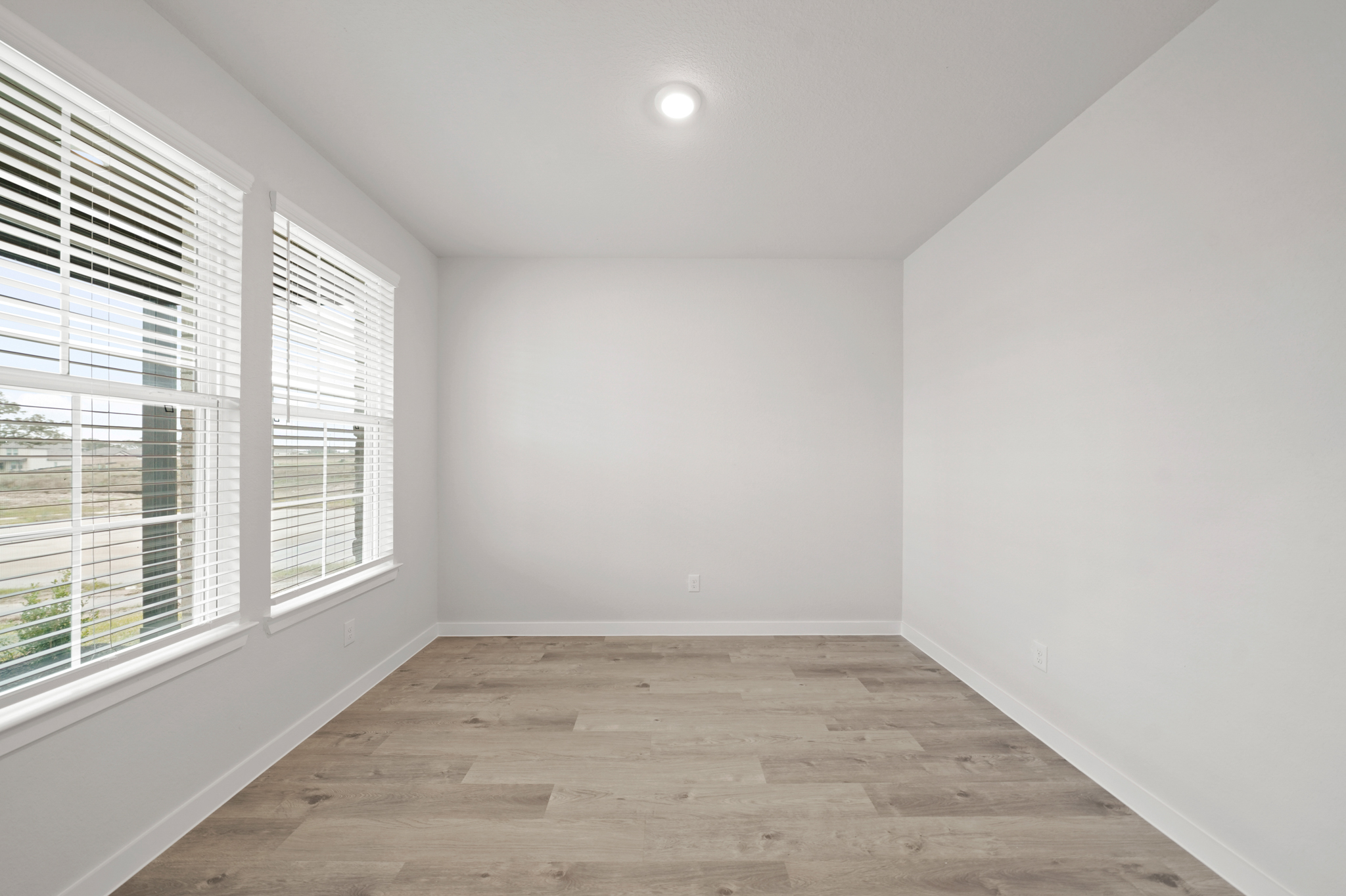 A room with windows and a wood floor.