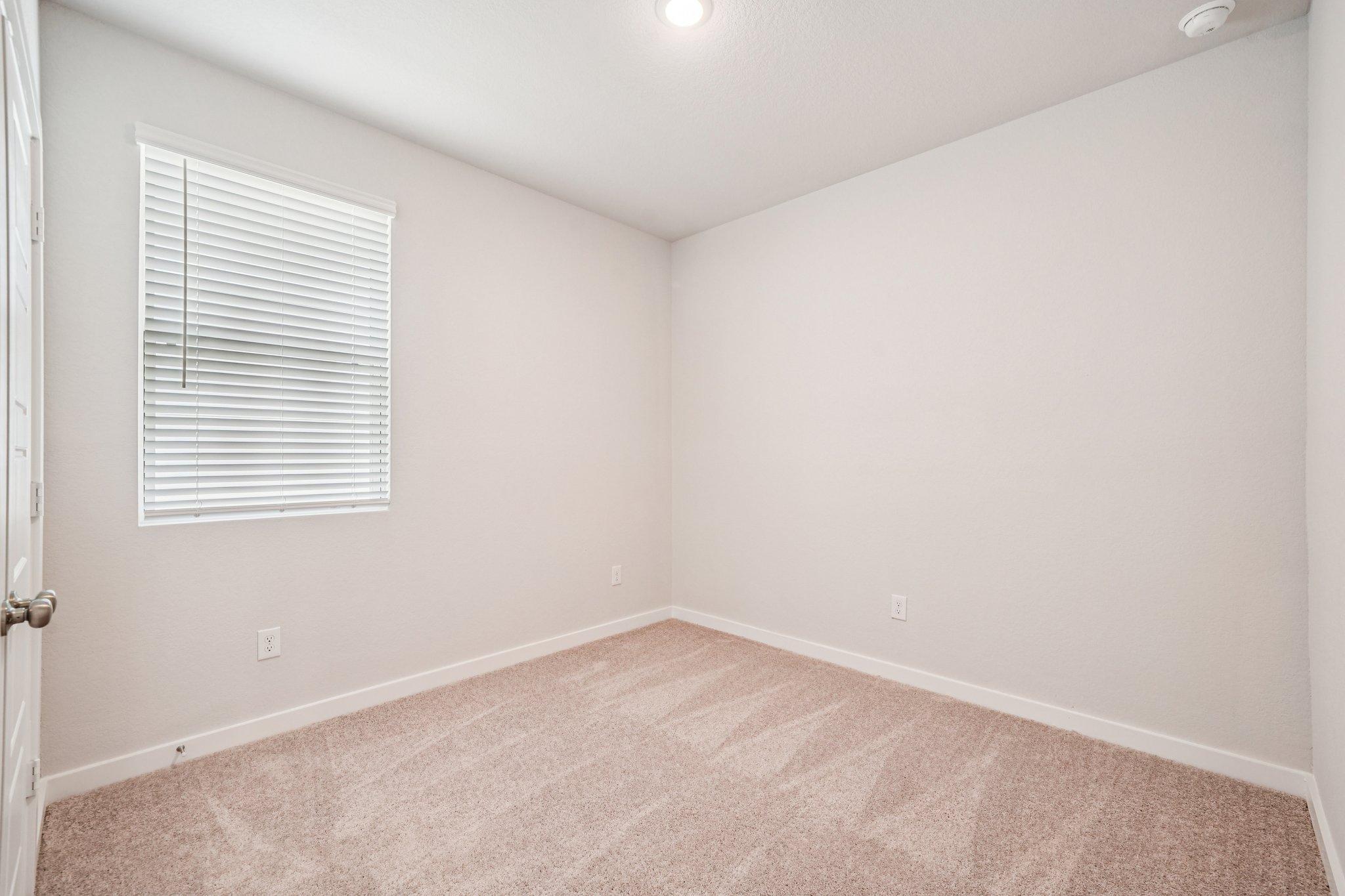 A room with a carpet and a window.