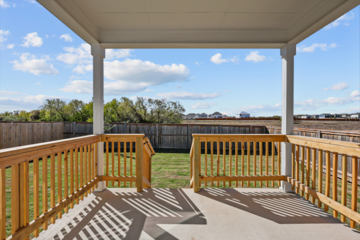 A deck with a railing and a body of water in the background.