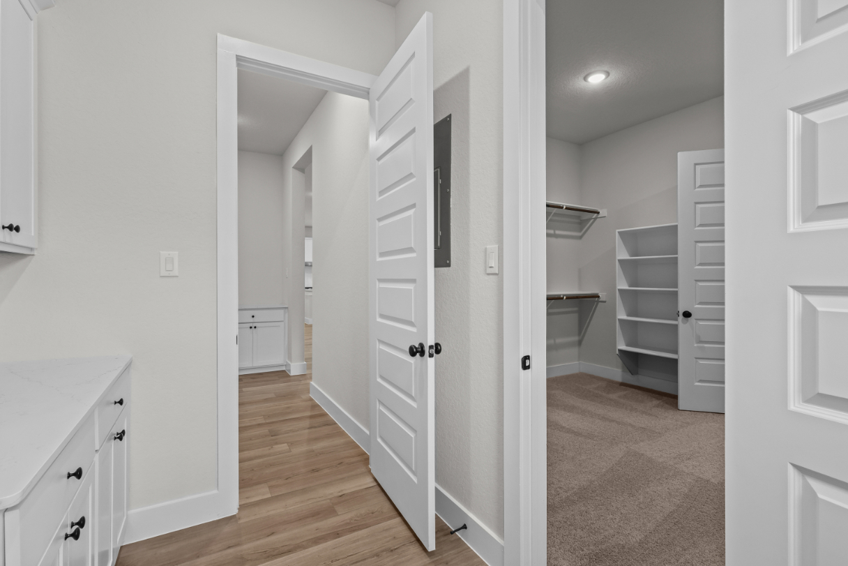 A hallway with white cabinets.