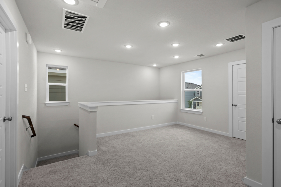 A large white room with a bathtub and a window.